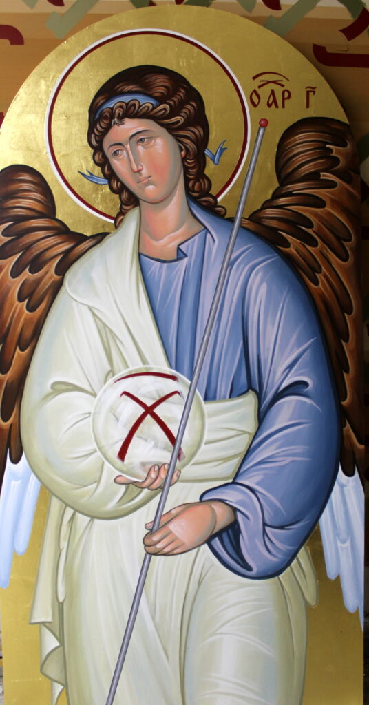 Angel in blue and white robes with dark wings and a gold-coloured halo, holding a staff and a round emblem marked in red.